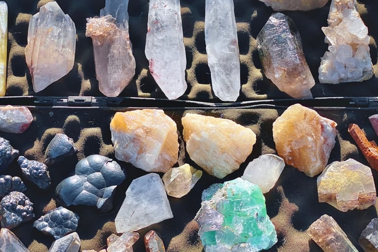 Una colección de cristales y minerales en bruto que incluye puntas de cuarzo transparente.