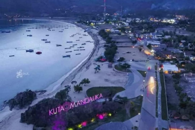 Aerial view of Kuta Mandalika beach in Lombok at twilight with boats, coastline, and city lights.