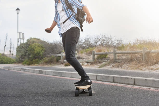man riding an electric skateboard on a paved road