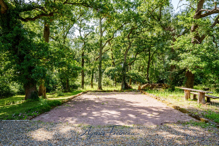 Terrain de pétanque privé en gravier, entouré de verdure et d’arbres, idéal pour les convives.