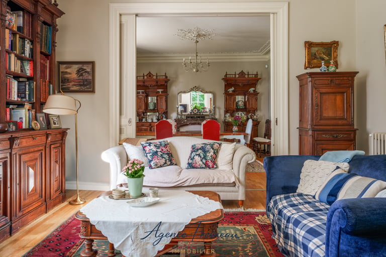 Élégant salon de style classique avec mobilier ancien en bois, canapé blanc et bibliothèque.