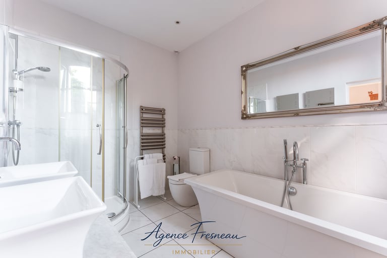 Salle de bains moderne avec douche d’angle à l’italienne, baignoire blanche et miroir.