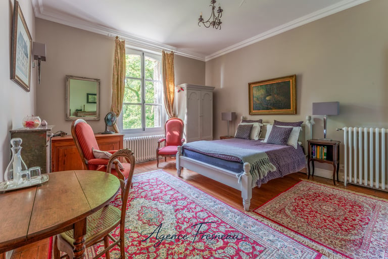 Élégante chambre de style classique avec lit en bois, tapis rouges à motifs et mobilier français.