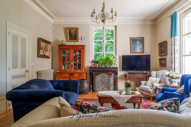 Élégant salon de style classique avec canapés en velours bleu, mobilier ancien en bois et cheminée.