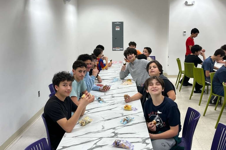 a group of students sitting at a long table enjoying ice cream and having fun
