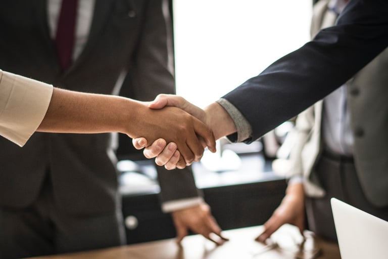a man and a woman in business attire shaking hands 