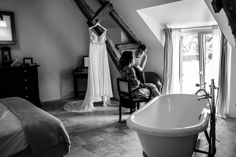 une future mariée se fait maquiller avec sa robe en arrière plan