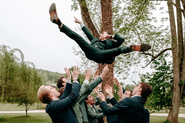 les garçons d'honneur font sauter le marié pendant le vin d'honneur