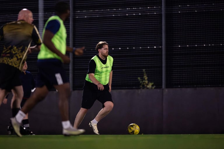 a man in a yellow vest and black shorts playing soccer