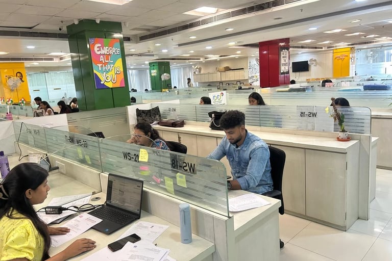 Diverse employees working at desks in a modern open-plan office workspace with laptop computers 