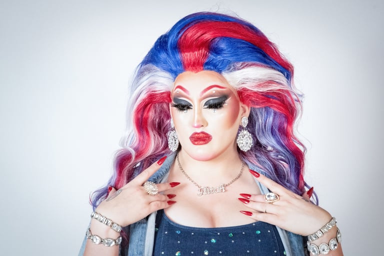 elagant headshot of drag queen pensively looking down with a large red, white, and blue wig