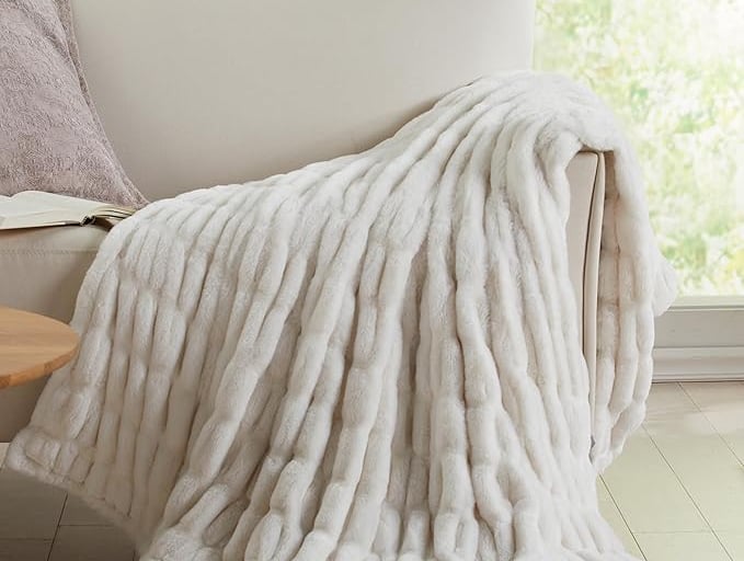 a white couch with a white plush blanket on it