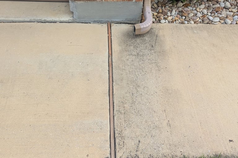 Before Picture of a sidewalk with a gutter downspout that stained the concrete.