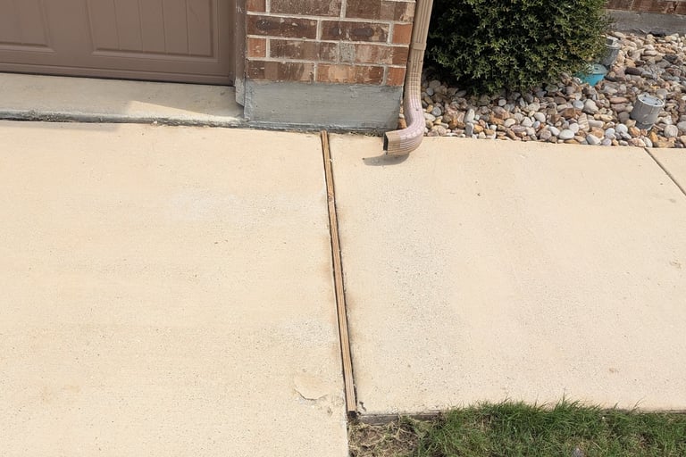 Picture of the cleaned sidewalk with the stain from the gutter downspout removed.  Ponder TX