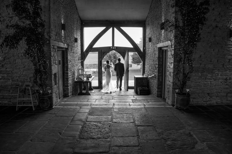 black and white image of newly weds in arch way 
