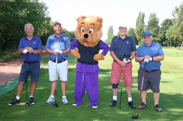 a group of people standing around a bear mascot