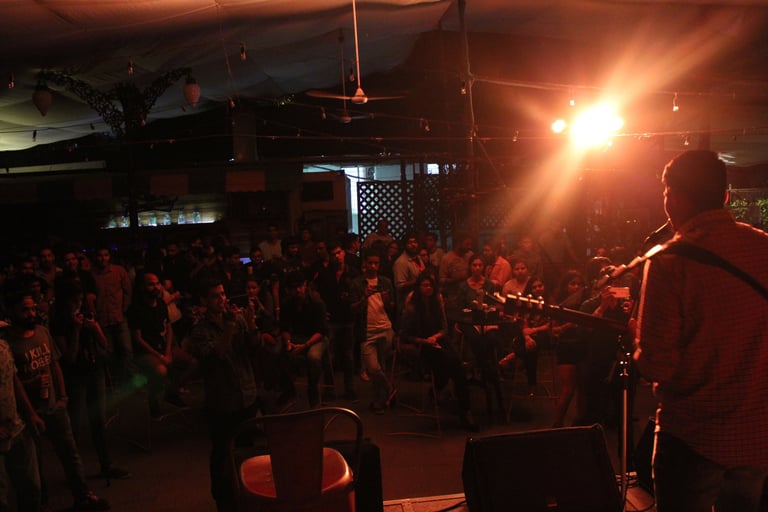 A singer songwriter performs in front of a substantial audience that is enjoying at a café.