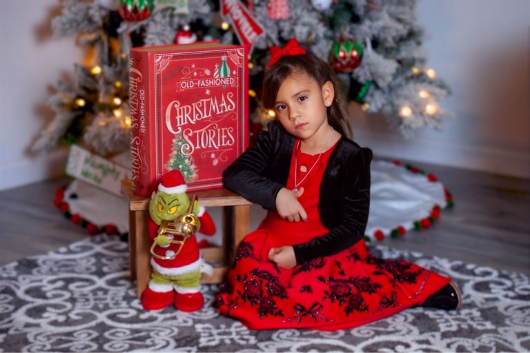 a little girl sitting on a chair with a book and a griner