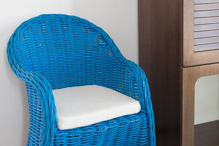 a wicker chair with a blue chair and a cabinet