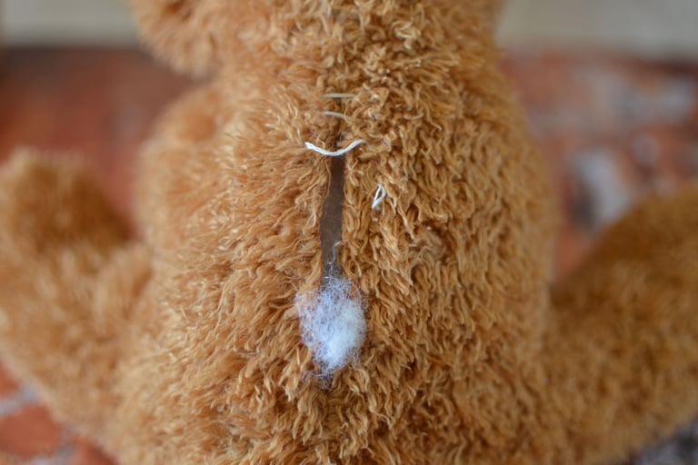 Gros plan sur une peluche abîmée avec rembourrage visible