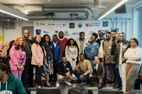 A group of diverse professionals posing for a photo at a technology networking event in a modern office.