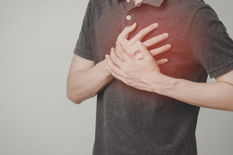 A man clutching his chest in pain, illustrating common heart attack symptoms and cardiac distress.