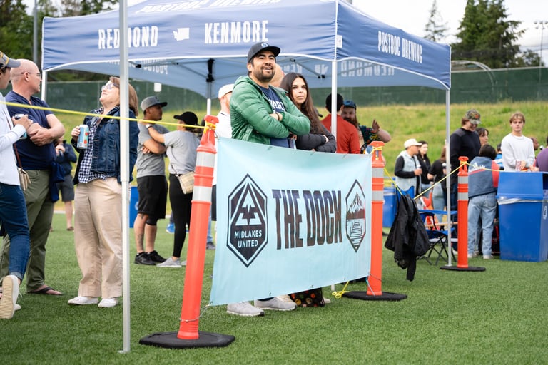 People standing by a sign that says "The Dock" drinking beer.