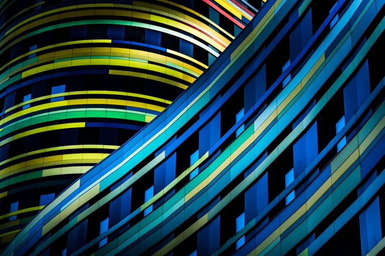 Abstract architecture photo of intersecting curved building facades with vibrant blue, green, and yellow panels.