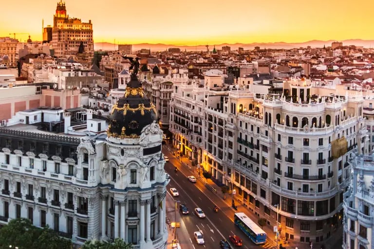 Sunset cityscape over Madrid, Spain featuring the historic Metropolis Building and Gran Via street.