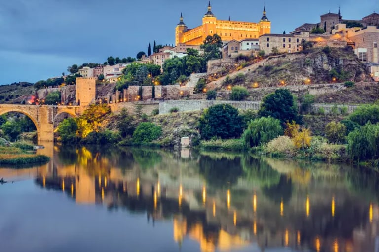Panoramic sunset view of Alcázar of Toledo fortress reflecting in the Tagus River in Spain.