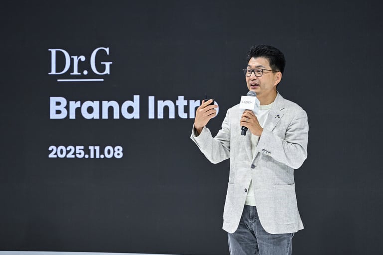 A man in a blazer gives a Dr.G skincare brand introduction presentation at a L'Oreal event.
