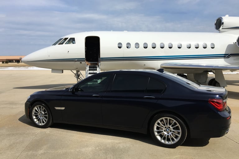 BMW 7 Series parked next to a Falcon 900EX on a ramp
