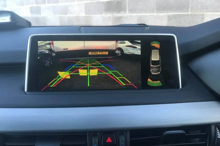 In-car dashboard screen showing live reversing camera view with coloured parking lines