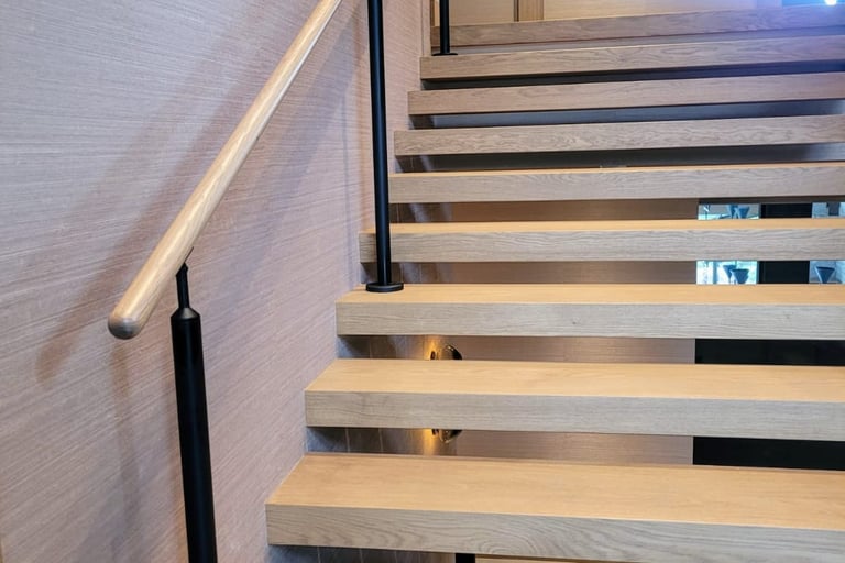 Floating staircase design with minimalist wood treads and slim black handrail in a modern home