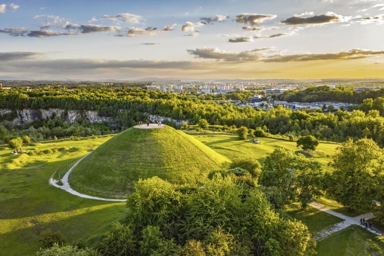 Aerial view of Krakus Mound in Krakow, Poland, surrounded by lush green parkland at sunset.