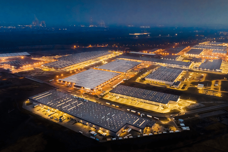 Aerial view of a large logistics park and distribution center illuminated at night with rows of warehouses.