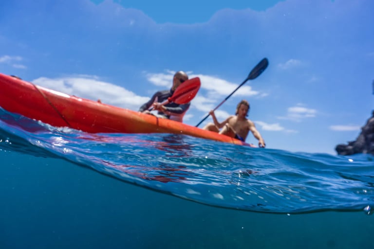 Two people on a red kayak on the open Atlantic Ocean near the coast of Funchal, Madeira