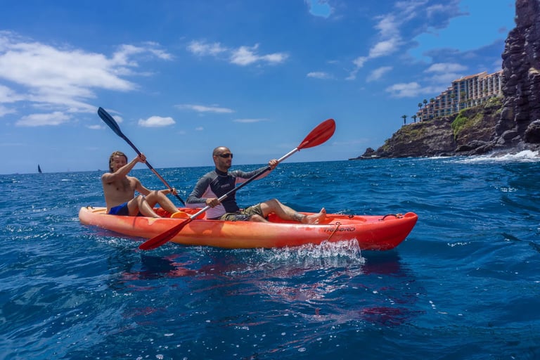 Tandem kayak on the deep blue Atlantic Ocean with the volcanic cliffs and hotel of Funchal in the background