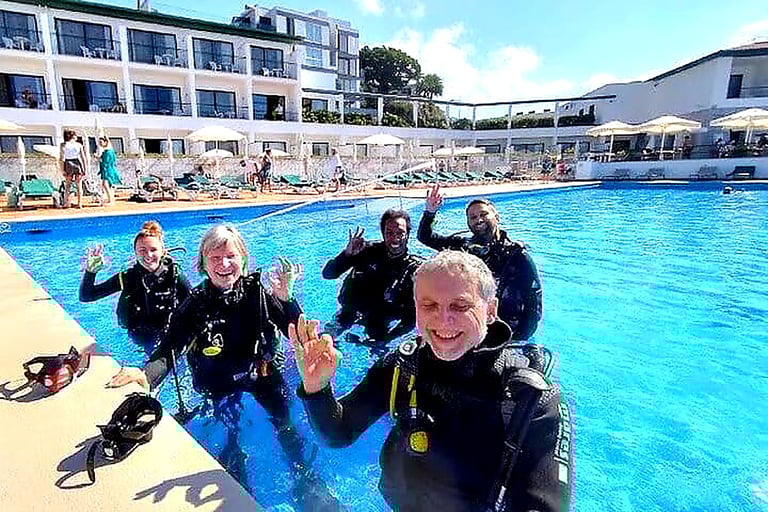 Happy group giving OK sign during try scuba diving experience at Quinta da Penha de França Mar pool, Madeira
