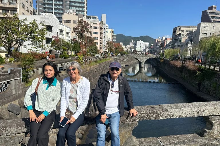A guide and a couple with Meganebashi Bridge in the background in Nagasaki