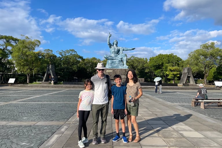 A family of four standing respectfully in front of the Peace Statue at Peace Park in Nagasaki