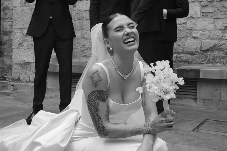 a bride holding a white bouquet of sweet peas and groomsmen are posing for a photo
