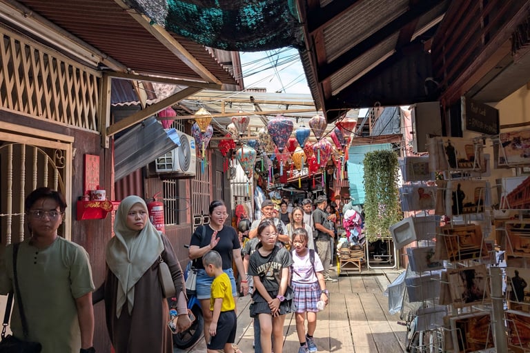 Tourists walk through a narrow street market at the historic Chew Jetty in Penang, Malaysia.