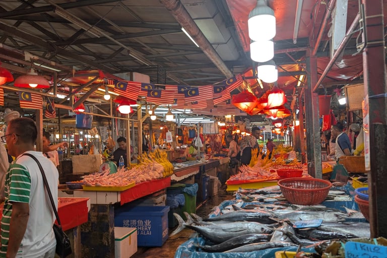 Fresh fish and seafood on display at a bustling Malaysian wet market with local vendors.