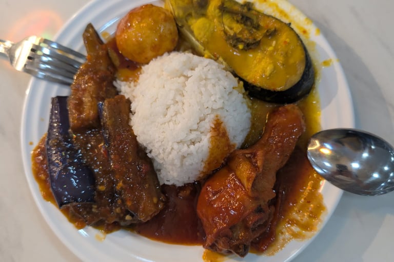 Nasi Lemak plate with steamed white rice, spicy sambal chicken, eggplant, and fish curry.