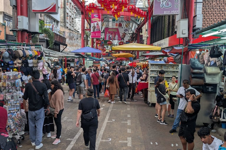 Crowded Petaling Street market in Kuala Lumpur Chinatown with red lanterns and street vendors.