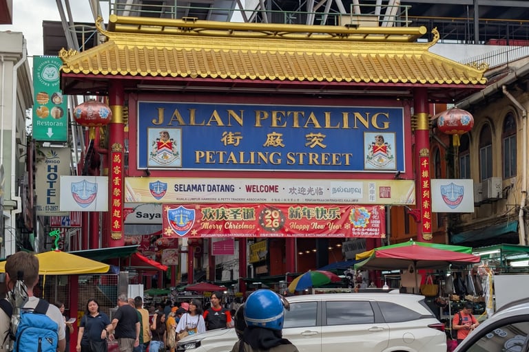 The iconic Petaling Street gate entrance to Kuala Lumpur Chinatown with busy street market and shoppers.