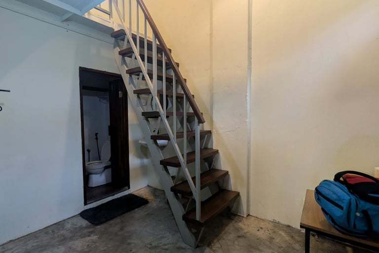Industrial style interior featuring open-tread stairs, concrete floor, and air conditioning unit.