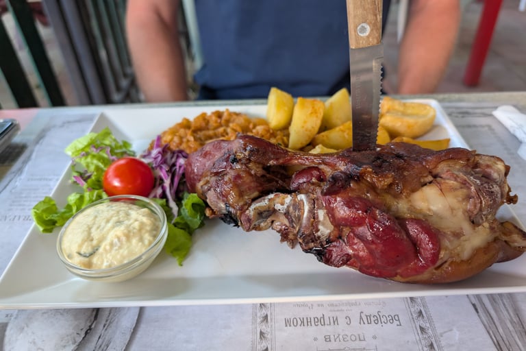 Roasted prk shank with potatoes and salad with a side of horses radish in Novi Sad, Serbia