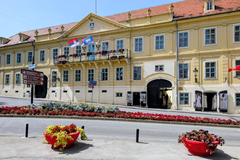 A yellow European style building near an intersection with flowers in Sremski Karlovci, Serbia